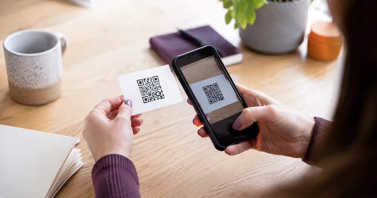 A phone camera scanning a clear QR code on a business card